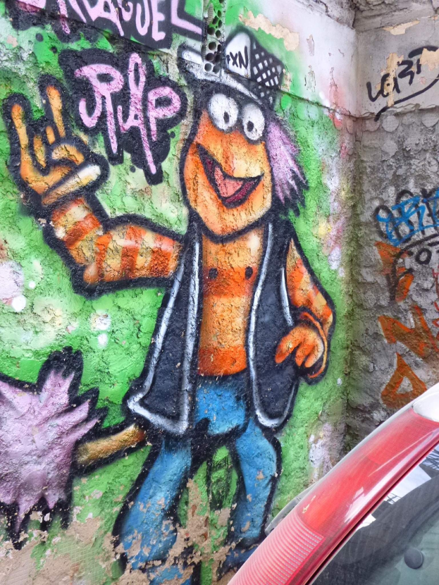 Ein rotes Auto vor einer Wand mit farbenfrohem Graffiti geparkt.