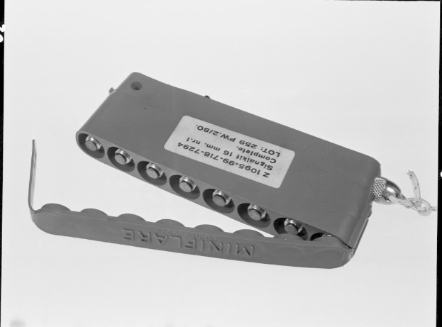 Schwarzes und weißes Foto eines metallenen Elektroschockers mit einer Kette, auf dem sichtbare Texte und Zahlen zu erkennen sind.