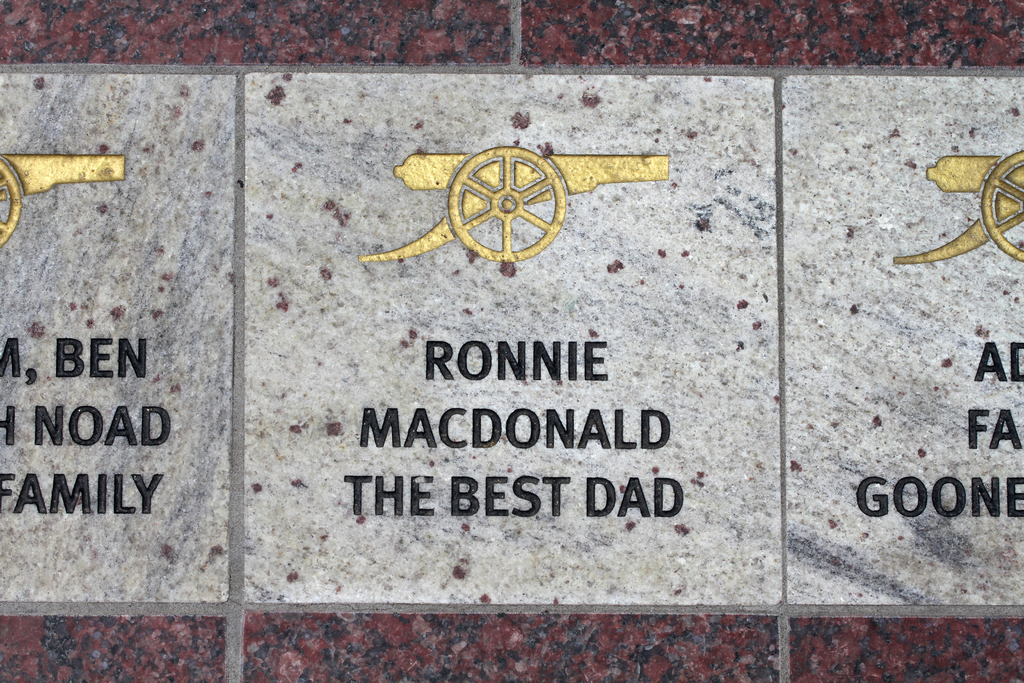 Historische Gedenktafel mit Symbolen und Text in der Mitte des Bildes.