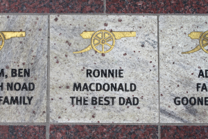 Historische Gedenktafel mit Symbolen und Text in der Mitte des Bildes.