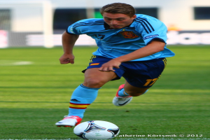 Ein Mann in einem blauen T-Shirt spielt Fußball auf einem Feld.