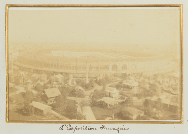 Altes Schwarz-Weiß-Foto eines Stadions in zentraler Lage in einer Stadt mit umliegenden Gebäuden, Bäumen und Strommasten sowie Text am unteren Bildrand.