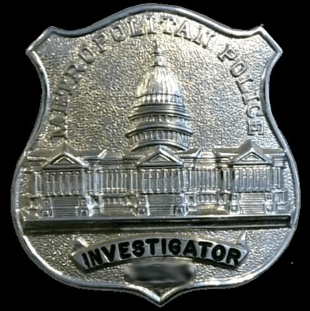 Ein silbernes Polizei-Detektivabzeichen mit der Gravur "Detektiv" auf einem weißen Hintergrund.