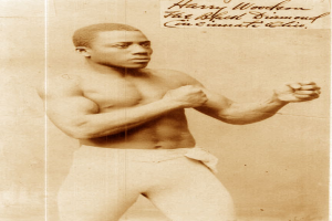 Ein Mann in einem Boxring, der Handschuhe und Shorts trägt und entschlossen in die Ferne blickt.