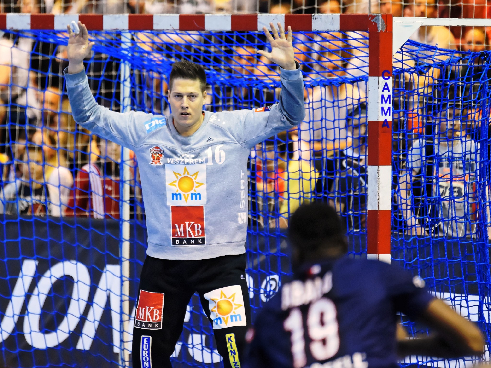 Handballspieler hebt die Hände in der Nähe eines Tores, mit einer Zuschauermenge im Hintergrund und einem "Futsal-Weltmeisterschaft 2019"-Schild im Hintergrund.