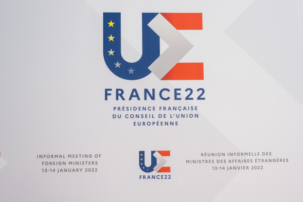 Plakat für die "Frankreich 22 - Informelle Zusammenkunft der Außenminister" mit dem Logo der Europäischen Union, das einen blauen Kreis, weißen Rahmen, weißen Stern und schwarzen zentrierten Text zeigt.