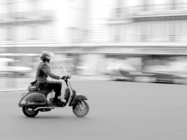 Person mit Roller auf der Straße unterwegs.