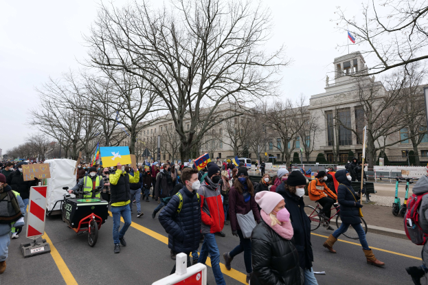 Eine große Gruppe von Menschen marschiert auf einer Straße in Washington, D.C. am 21. Januar 2020, einige halten Schilder und andere fahren Fahrräder, mit Bäumen und einem klaren blauen Himmel im Hintergrund.