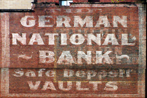 Eine Ziegelwand mit einem Schild, auf dem "Deutsche Nationalbank-Schließfächer" steht, und einem Fenster oben.
