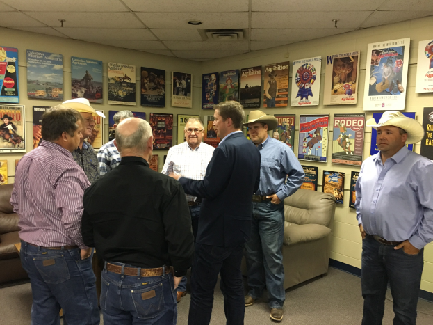 Gruppe von Männern in einem Raum mit Sofas, Postern und Deckenleuchten in ein Gespräch vertieft.