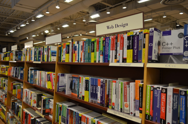 Ein Bibliotheksinneres mit Bücherregalen, Texttafeln, Deckenleuchten und sichtbaren Rohren.