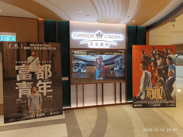 Eintritt zu den Kaiserkinos in Hong Kong mit Bannern, einem Bildschirm, einer Namensschild, Deckenbeleuchtung und einem Wasserzeichen.