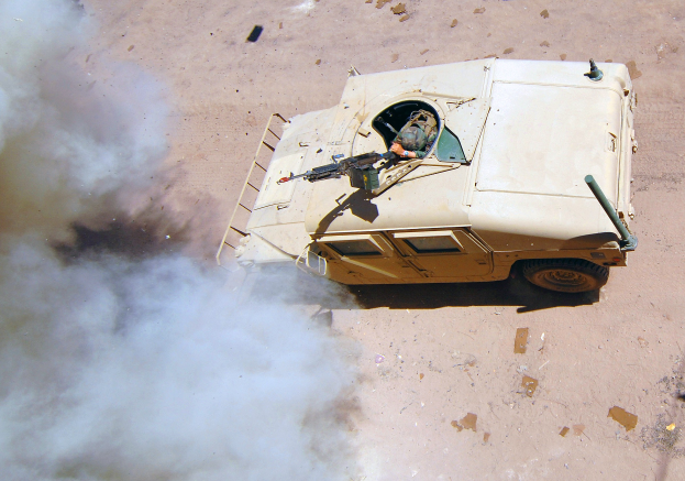 Panzerfahrzeug fährt auf einem Schotterweg mit Rauchentwicklung und einer Person im Inneren.