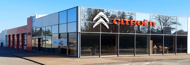 Außenansicht eines Citroën-Geschäfts mit Glaswänden und -türen, einer Straße davor und einem klaren blauen Himmel.