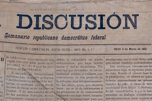 Ein gelblich, leicht zerknittertes Zeitungsblatt mit der schwarzen Aufschrift "Diskussion", das die Schlagzeile "Semanario Repúblicano Democrático Federal" trägt.