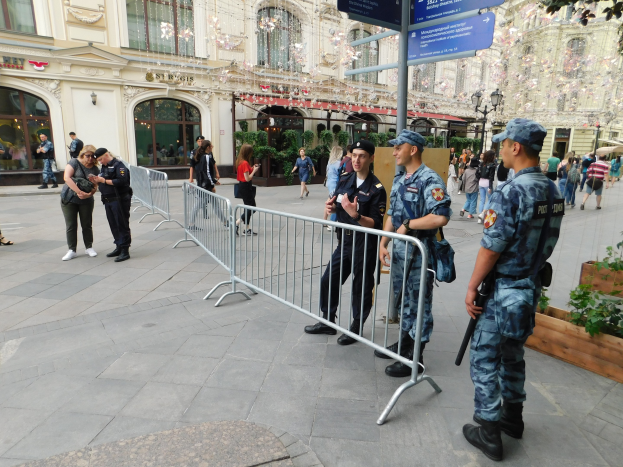 Polizeibeamte in Uniform stehen hinter Absperrungen einer Menge gegenüber, einige tragen Mützen und halten Waffen, mit Gebäuden, Bäumen und Schildern im Hintergrund in Wien während einer Anti-Terror-Operation.