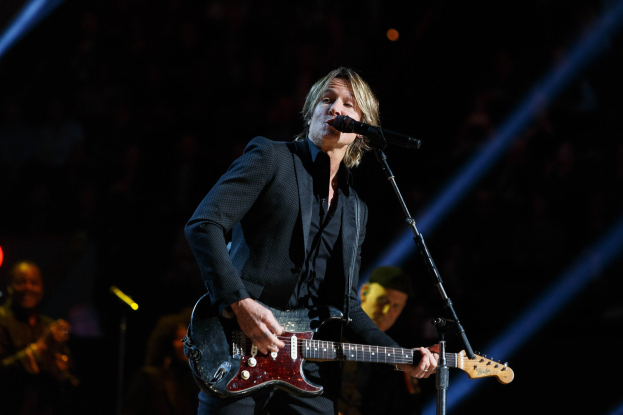Keith Urban performs auf der Bühne im Joint im Hard Rock Hotel & Casino in Las Vegas, spielt Gitarre mit einem Mikrofon vor sich und Bandmitgliedern im Hintergrund bei gedämpfter Beleuchtung.