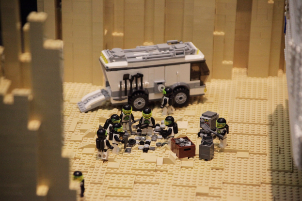Lego-Modell einer Star-Wars-Szene mit einem Fahrzeug im Vordergrund und verstreuten Spielzeugen sowie einer Wand im Hintergrund.