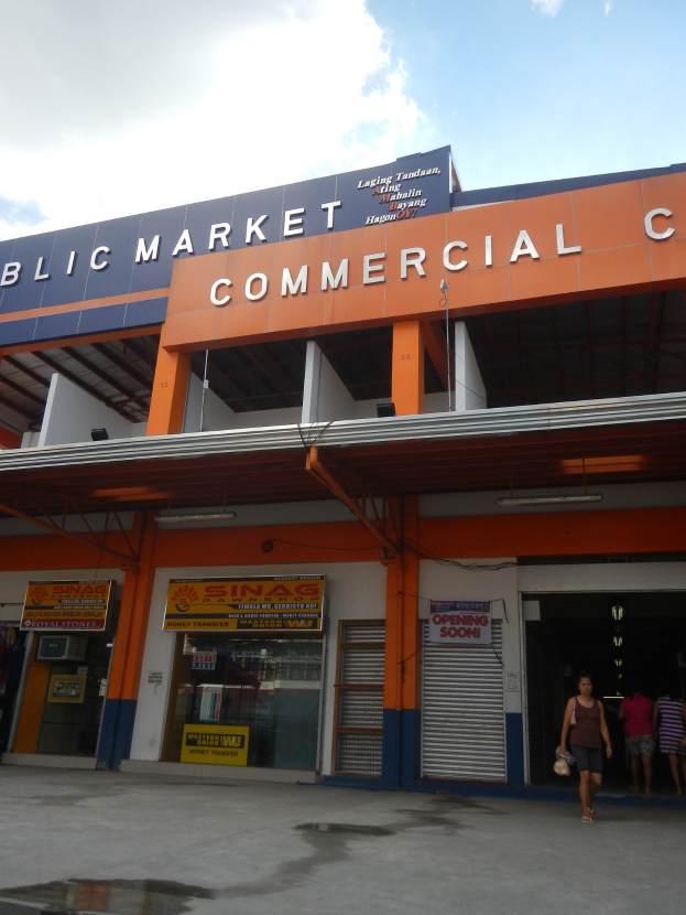 Öffentliches Marktzentrum mit Menschen vorneweg, Text an dem Gebäude und Himmel darüber.