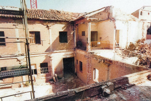 Ein teilweise abgerissenes Gebäude mit einer Barriere, sichtbaren Fenstern und etwas, das wie eine Leiter aussieht.