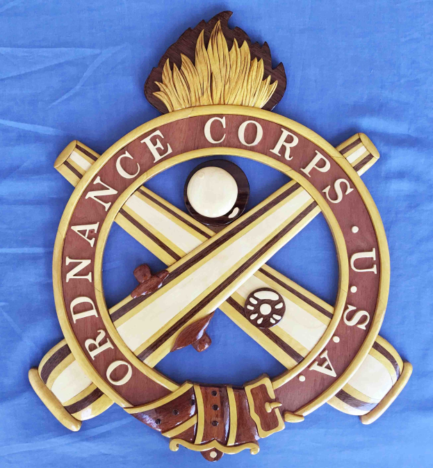 Holztafel mit 'Ordnance Corps'-Text, verziert mit einem geschnitzten weißen Stern auf navy-Blue-Hintergrund mit goldener Umrandung, montiert auf blauem Tuch in fetter schwarzer Schrift.