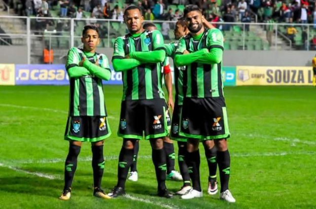 Männer in grüner und schwarzer Uniform auf einem Fußballfeld feiernd mit Zuschauern im Hintergrund.