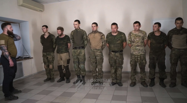 Gruppe von Männern in Militäruniformen, die in einem Raum mit einer wandmontierten Klimaanlage, einer Tür auf der rechten Seite und einem Tisch mit Gegenständen stehen; die Bildunterschrift lautet "Sergei Vorobyov und sein Team" unten.