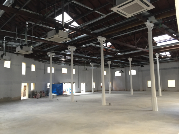 Großes Industriehallenareal mit zahlreichen Fenstern, tragenden Säulen und Deckenleuchten sowie Klimaanlagen, verfügbar zur Miete.