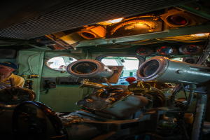 Das Innere eines Zuges mit Sitzen und verschiedenen Gegenständen, eine Person in einem gelben T-Shirt steht links.