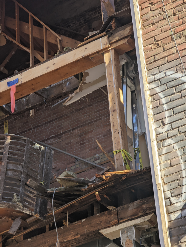 Ein teilweise abgerissener Bau mit verstreuten Holzplanken und Trümmern, mit zerbrochenen Fenstern und Türen.