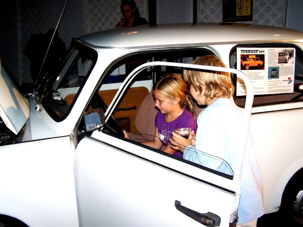 Zwei Kinder versuchen in ein Auto mit mehreren anderen Menschen in der Nahe einzusteigen.